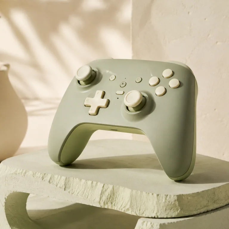 Sage green game controller on a pale stone pedestal